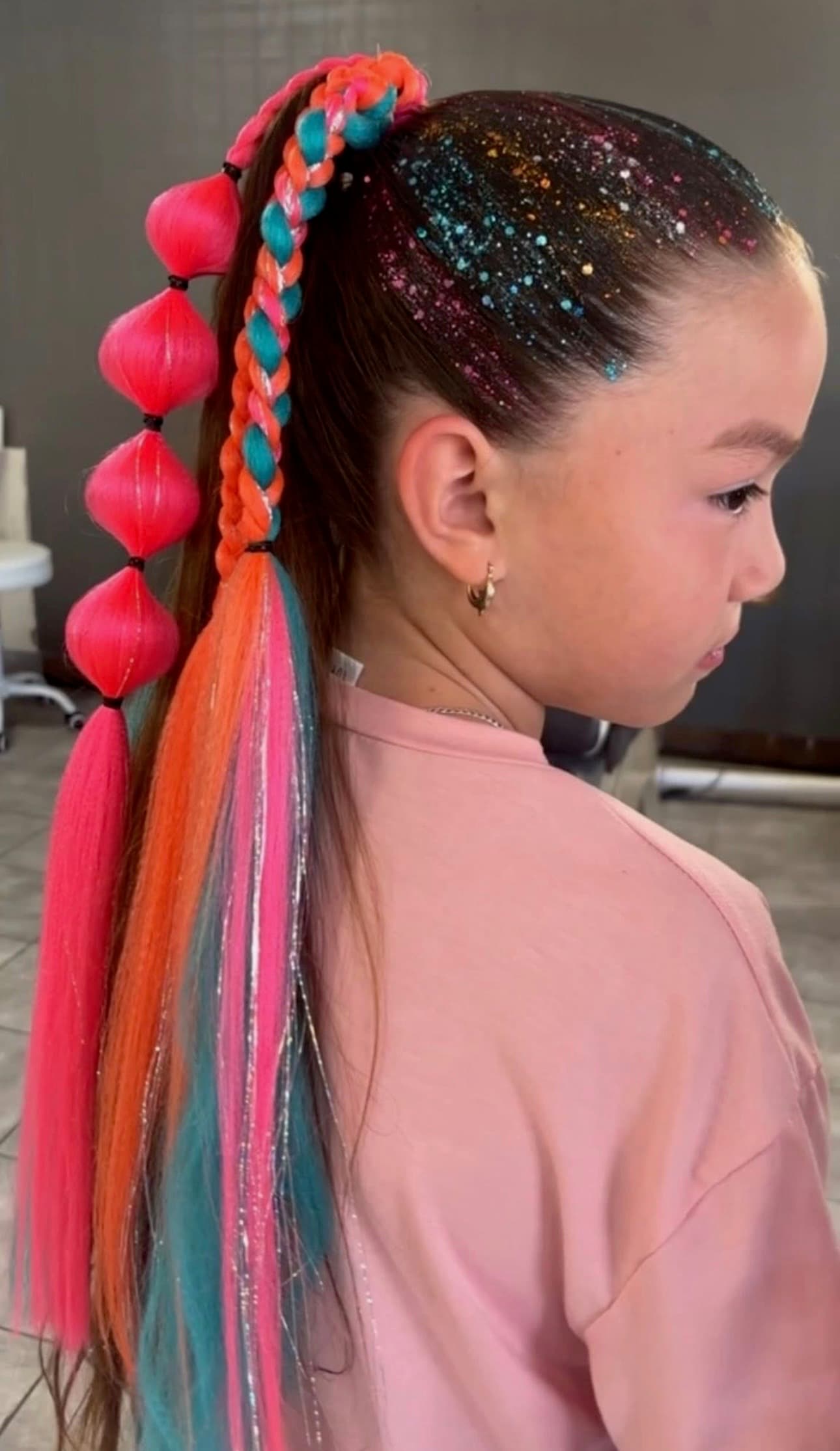 An image of a girl with bright colored hair extensions styled in various types of braids.