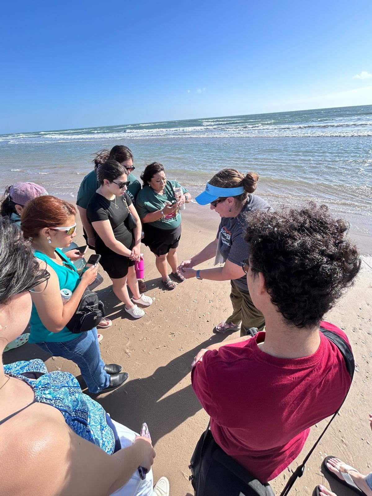 An image of people standing around in a circle on a beach