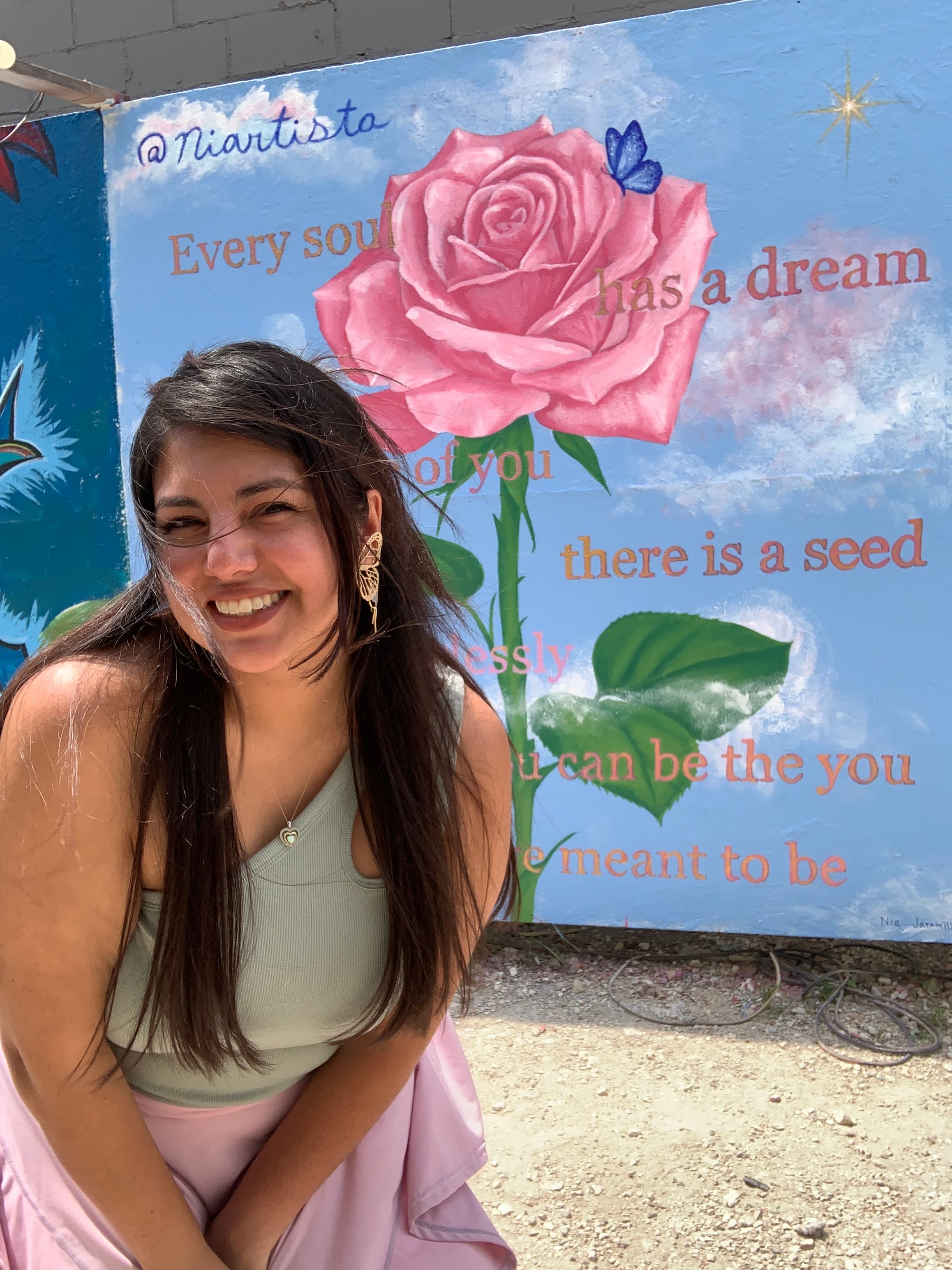 Niartista in front of a flower mural