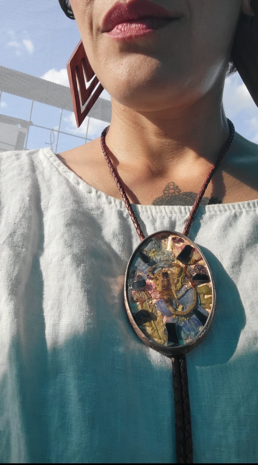 Dia Luna Arts wearing a pendant with flowers, rocks, and a bark scorpion in it